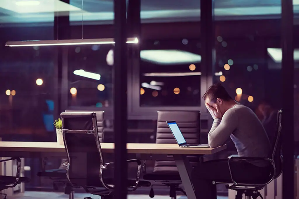 Mand arbejder på laptop i mørkt kontor uden Office 365 backup