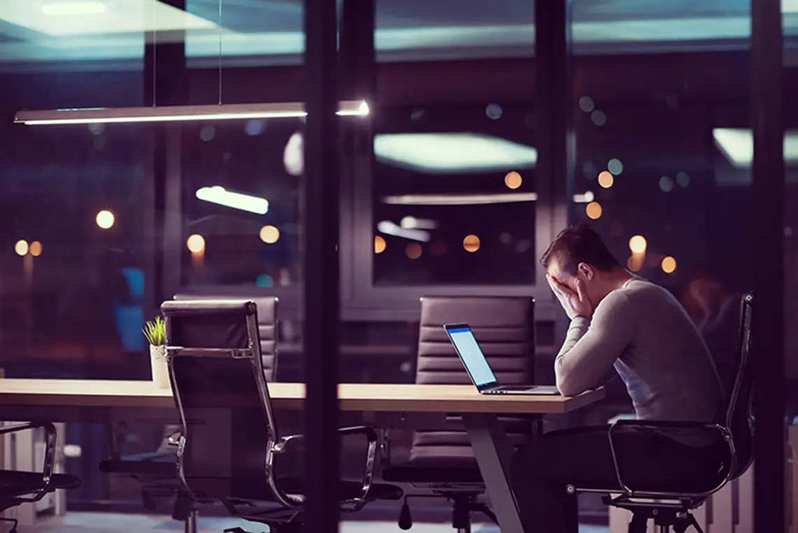 Mand arbejder på laptop i mørkt kontor uden Office 365 backup