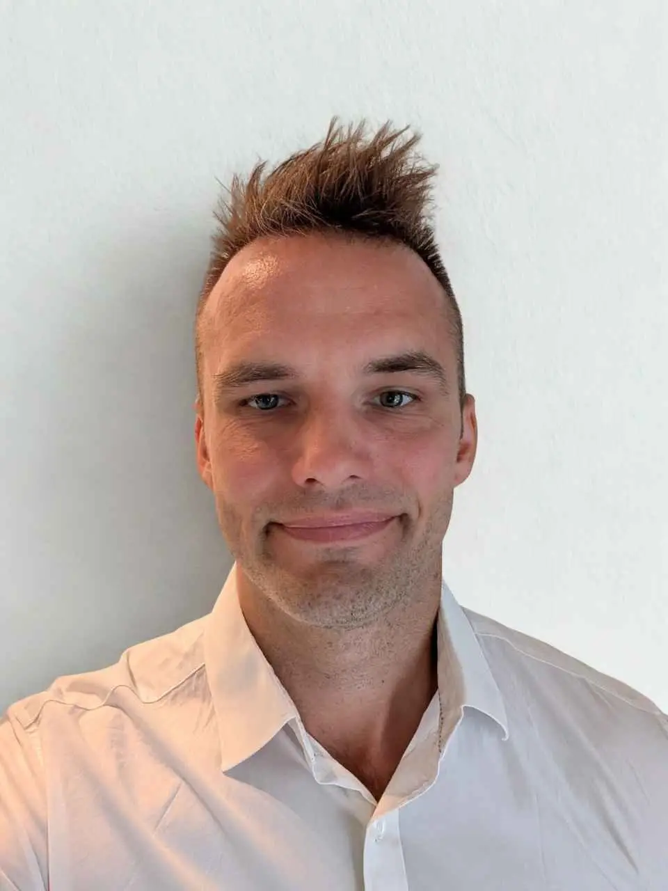 Dennis, account manager, smiler til kamera i professionel arbejdssituation